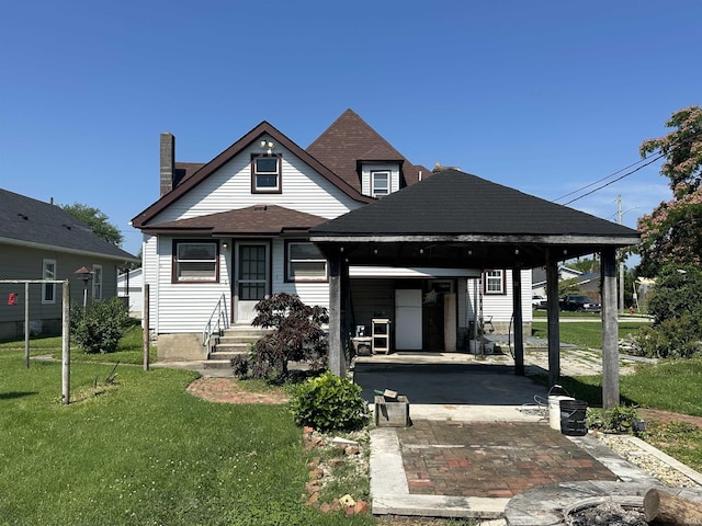 448 N 7th St, Mitchell, IN 47446 - view of front of house featuring a front lawn, a carport, entry steps, a shingled roof, and driveway