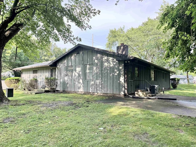 3105 Perrysburg Rd, Logansport, IN 46947 - view of side of home with board and batten siding, a chimney, and a yard