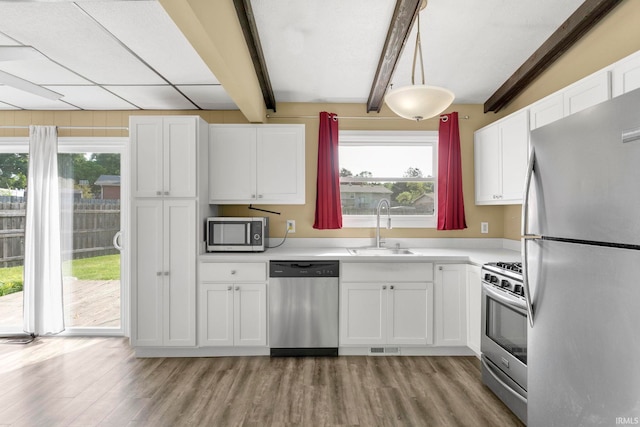 51278 Arch St, Granger, IN 46530 - kitchen with appliances with stainless steel finishes, beam ceiling, white cabinetry, light wood-style flooring, and plenty of natural light