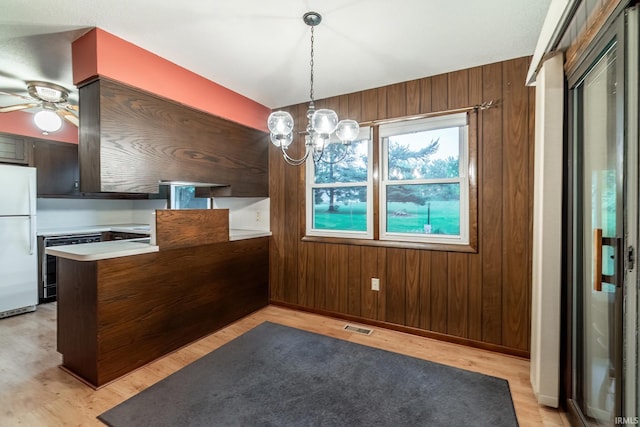 9246 Fritz Rd, Fort Wayne, IN 46818 - unfurnished dining area with light wood-type flooring, a chandelier, wood walls, and a ceiling fan