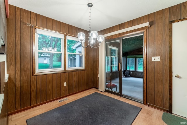 9246 Fritz Rd, Fort Wayne, IN 46818 - unfurnished dining area featuring light wood-style floors, wooden walls, and a chandelier