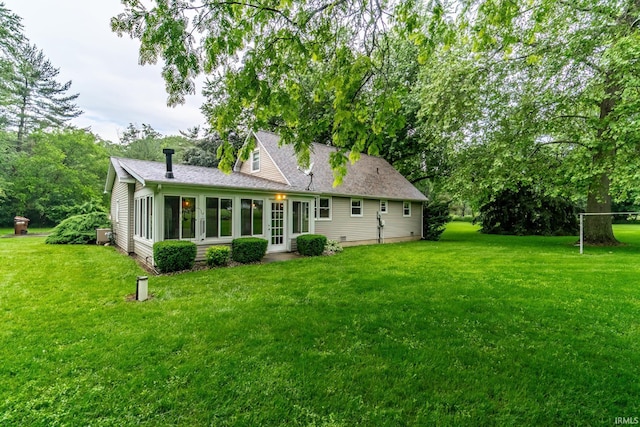 9246 Fritz Rd, Fort Wayne, IN 46818 - rear view of house featuring a lawn, a shingled roof, and a sunroom