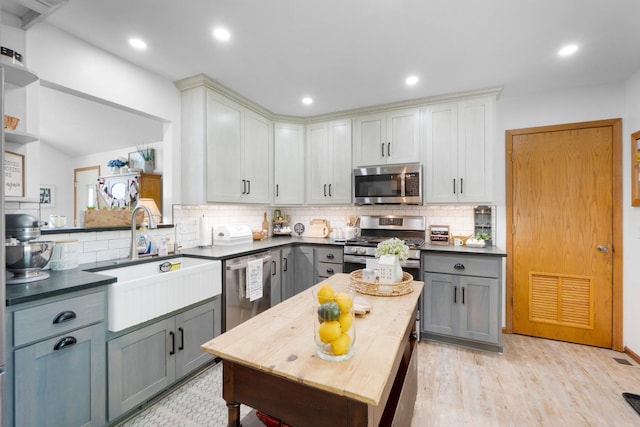 3139 E Colony Ave, Columbia City, IN 46725 - kitchen with stainless steel appliances, dark countertops, gray cabinetry, backsplash, and light wood-style floors