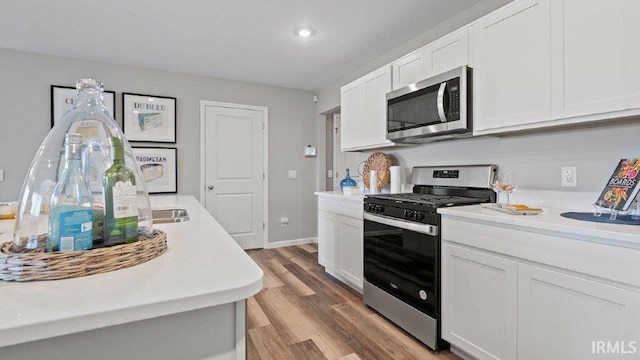1185 Catesby Ct, Fort Wayne, IN 46818 - kitchen with appliances with stainless steel finishes, light countertops, white cabinetry, light wood-type flooring, and recessed lighting