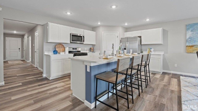 1185 Catesby Ct, Fort Wayne, IN 46818 - kitchen featuring appliances with stainless steel finishes, light wood-type flooring, white cabinets, a breakfast bar area, and recessed lighting