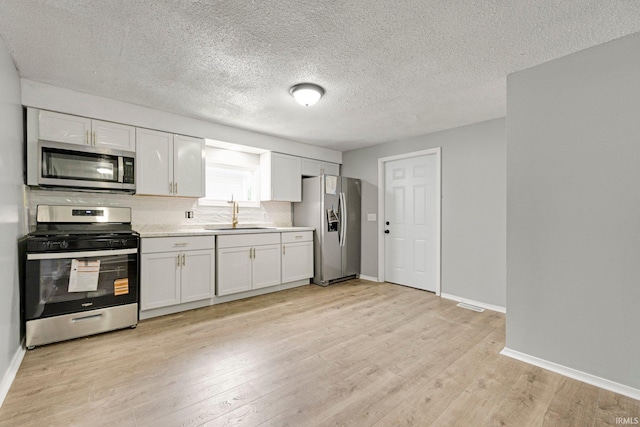 2725 Fox Ave, Fort Wayne, IN 46807 - kitchen featuring stainless steel appliances, light wood-style flooring, light countertops, white cabinetry, and a textured ceiling