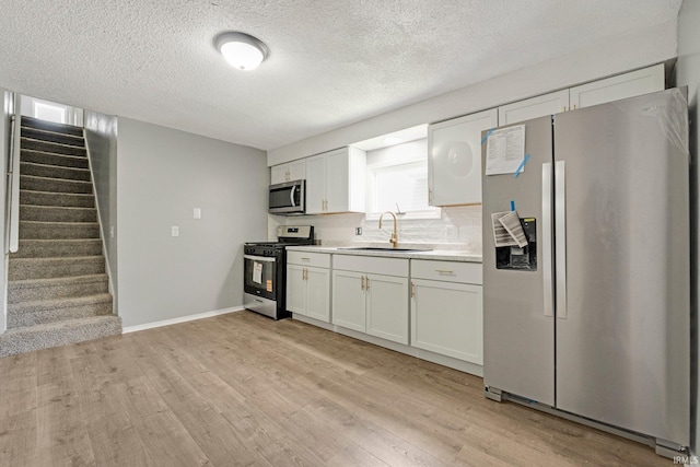 2725 Fox Ave, Fort Wayne, IN 46807 - kitchen with appliances with stainless steel finishes, light countertops, light wood-type flooring, a textured ceiling, and white cabinetry