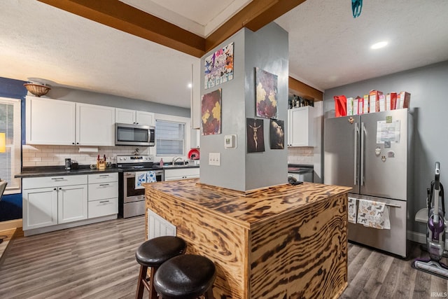 919 S 18th St, Lafayette, IN 47905 - kitchen featuring appliances with stainless steel finishes, light wood-style flooring, backsplash, white cabinetry, and a textured ceiling