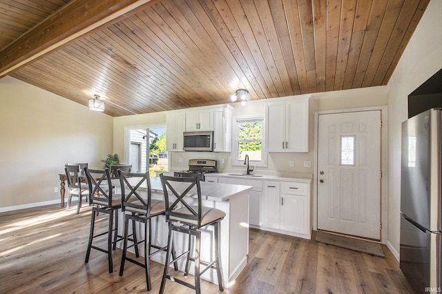 56435 Eastlea Dr, South Bend, IN 46619 - kitchen with stainless steel appliances, a kitchen island, wooden ceiling, white cabinets, and a kitchen breakfast bar