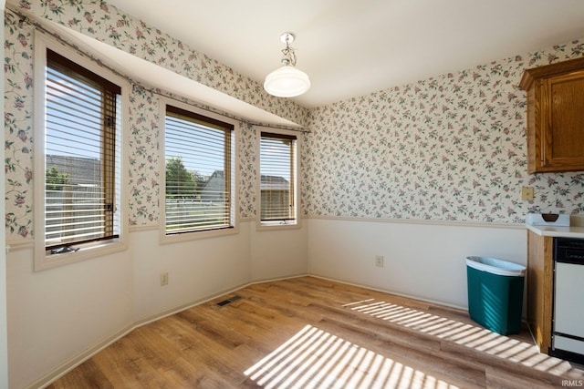 1408 Duesenberg Dr, Auburn, IN 46706 - unfurnished dining area featuring wallpapered walls, light wood-style floors, and wainscoting