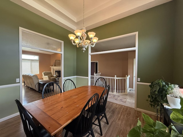 9825 Tamar Trl, Fort Wayne, IN 46825 - dining room featuring a chandelier, wood finished floors, a fireplace, and a tray ceiling