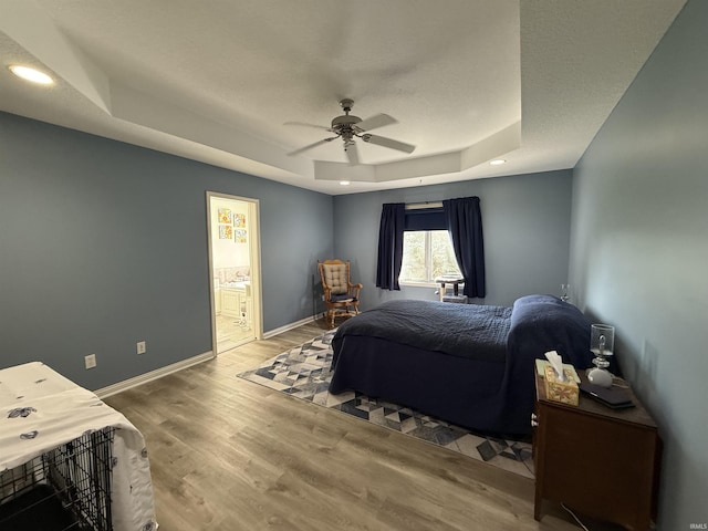 9825 Tamar Trl, Fort Wayne, IN 46825 - bedroom featuring a tray ceiling, wood finished floors, ensuite bath, recessed lighting, and ceiling fan