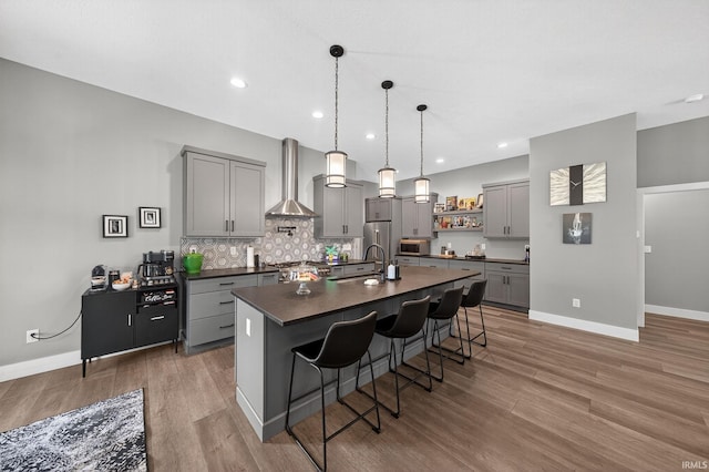 1229 Corby Blvd, South Bend, IN 46617 - kitchen with gray cabinetry, dark countertops, wall chimney range hood, stainless steel appliances, and a kitchen breakfast bar