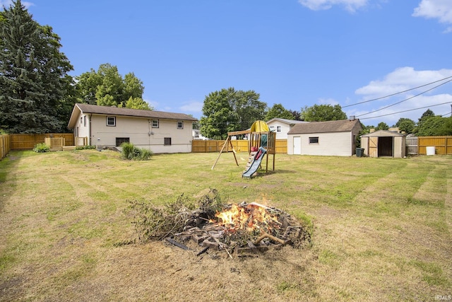 19545 Hildebrand St, South Bend, IN 46614 - fenced backyard featuring a storage unit, a fire pit, and a playground