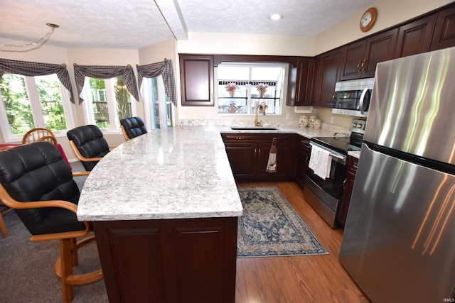 9841 S Harbour Pointe Dr, Bloomington, IN 47401 - kitchen with appliances with stainless steel finishes, a peninsula, a textured ceiling, open floor plan, and wood finished floors