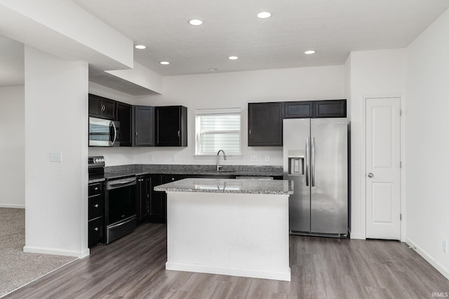 197 Folkston Way, Lafayette, IN 47905 - kitchen with appliances with stainless steel finishes, wood finished floors, a kitchen island, recessed lighting, and light stone countertops