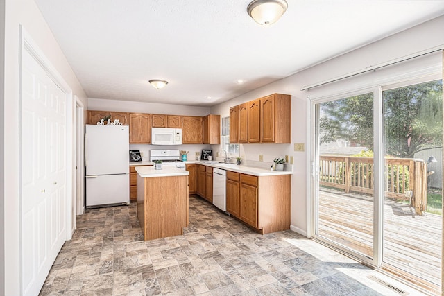 4211 Anchor Dr, Mishawaka, IN 46544 - kitchen featuring white appliances, light countertops, a center island, stone finish floors, and brown cabinetry