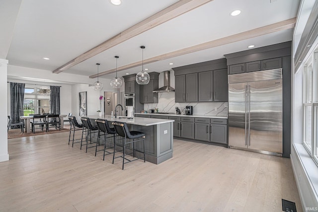 18419 Donegal Dr, South Bend, IN 46637 - kitchen with appliances with stainless steel finishes, wall chimney range hood, a breakfast bar, light countertops, and beam ceiling