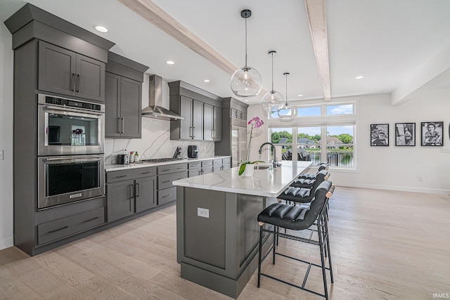 18419 Donegal Dr, South Bend, IN 46637 - kitchen featuring wall chimney exhaust hood, appliances with stainless steel finishes, beam ceiling, light wood-style floors, and a breakfast bar