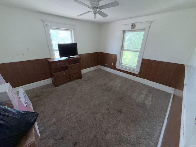 1800 High St, Logansport, IN 46947 - unfurnished living room with a wainscoted wall, wooden walls, carpet, and a ceiling fan