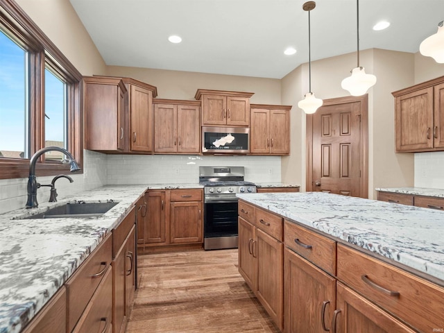 188 Begonia Ct, Fort Wayne, IN 46814 - kitchen with appliances with stainless steel finishes, light wood finished floors, pendant lighting, decorative backsplash, and brown cabinetry
