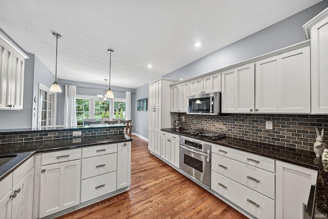 51733 Copperfield Rdg, Granger, IN 46530 - kitchen featuring appliances with stainless steel finishes, wood finished floors, backsplash, decorative light fixtures, and white cabinetry