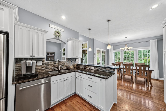 51733 Copperfield Rdg, Granger, IN 46530 - kitchen with appliances with stainless steel finishes, decorative backsplash, a peninsula, white cabinets, and hanging light fixtures