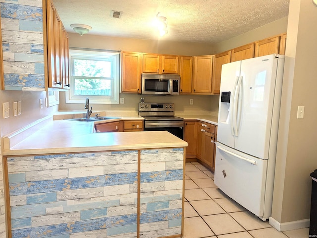 2220 Bobolink Dr, West Lafayette, IN 47906 - kitchen with stainless steel appliances, light countertops, a peninsula, a textured ceiling, and light tile patterned floors
