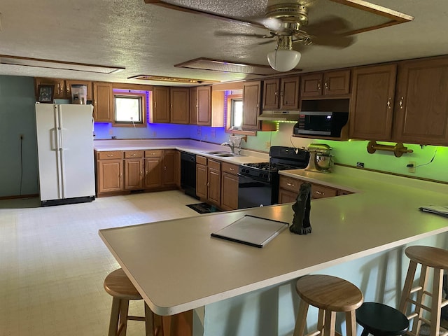 1802 Delphi Ave, Frankfort, IN 46041 - kitchen featuring black appliances, under cabinet range hood, a breakfast bar, light countertops, and a textured ceiling