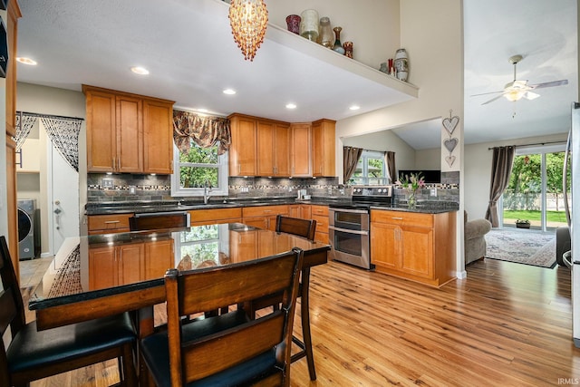 54410 Pleasant Valley Dr, Osceola, IN 46561 - kitchen with range with two ovens, washer / dryer, light wood-style floors, dishwashing machine, and backsplash
