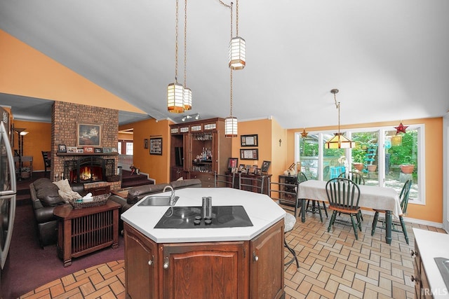 1760 Grant St, Elkhart, IN 46514 - kitchen with black electric cooktop, brick patterned floors, vaulted ceiling, light countertops, and a brick fireplace