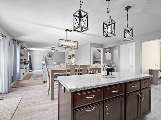 2479 Trillium Cv, Huntertown, IN 46748 - kitchen with ceiling fan, pendant lighting, dark brown cabinets, and light wood-style floors
