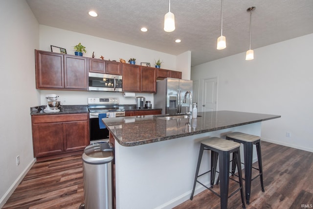 6471 Wallingford St, Lafayette, IN 47905 - kitchen featuring appliances with stainless steel finishes, dark wood-style flooring, a breakfast bar, a textured ceiling, and a center island with sink