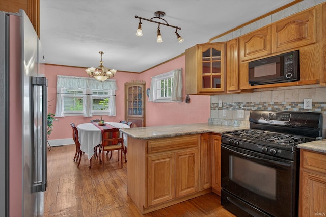 412 Tonti Ave, South Bend, IN 46617 - kitchen with black appliances, a chandelier, a peninsula, decorative backsplash, and glass insert cabinets