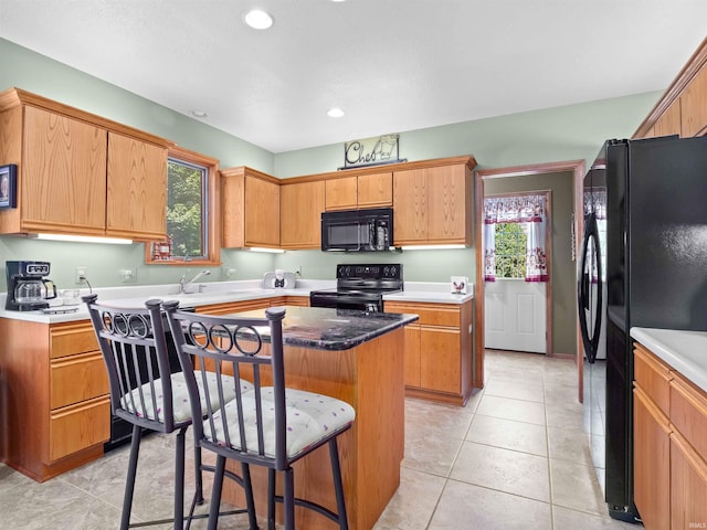 6709 Shag Bark Ct, Fort Wayne, IN 46835 - kitchen with black appliances, a kitchen island, a breakfast bar, light tile patterned flooring, and recessed lighting