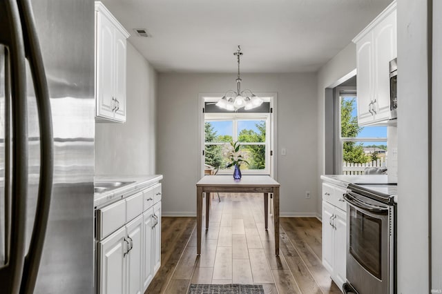 12909 Cocoplum Ct, Fort Wayne, IN 46814 - kitchen featuring stainless steel appliances, white cabinets, light countertops, a chandelier, and wood finished floors