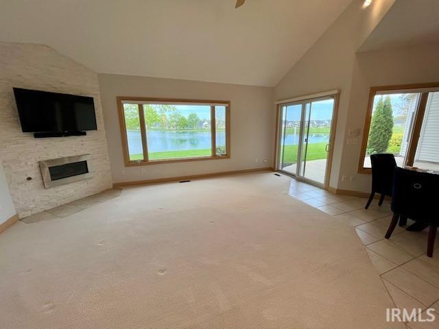 8018 Inverness Lakes Trl, Fort Wayne, IN 46804 - living area with light carpet, a stone fireplace, high vaulted ceiling, light tile patterned flooring, and a water view