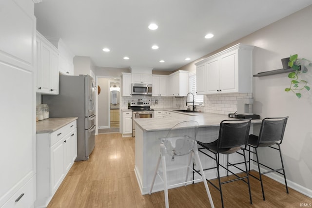 9628 Trading Post Rd, Leo, IN 46765 - kitchen with stainless steel appliances, a peninsula, white cabinetry, light wood finished floors, and recessed lighting
