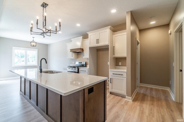 7751 Luna Way, Fort Wayne, IN 46835 - kitchen featuring stainless steel range with gas cooktop, a large island with sink, white cabinetry, light countertops, and a chandelier