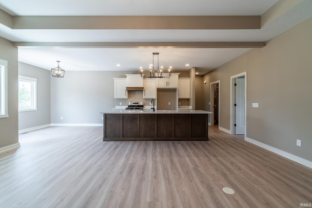 7751 Luna Way, Fort Wayne, IN 46835 - kitchen featuring a chandelier, stainless steel range oven, light wood-style floors, a large island with sink, and light countertops