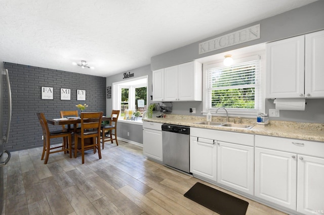 4831 Woodford Dr, Fort Wayne, IN 46835 - kitchen featuring stainless steel dishwasher, light countertops, white cabinetry, light wood-style floors, and brick wall