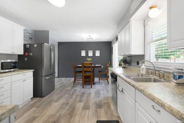 4831 Woodford Dr, Fort Wayne, IN 46835 - kitchen with stainless steel appliances, white cabinets, light wood-style floors, light countertops, and brick wall