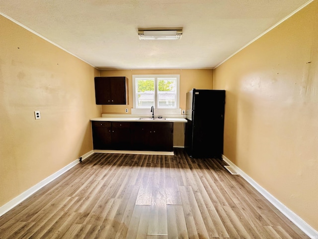 120 W Warren St, Mitchell, IN 47446 - kitchen with freestanding refrigerator, ornamental molding, dark brown cabinets, wood finished floors, and light countertops