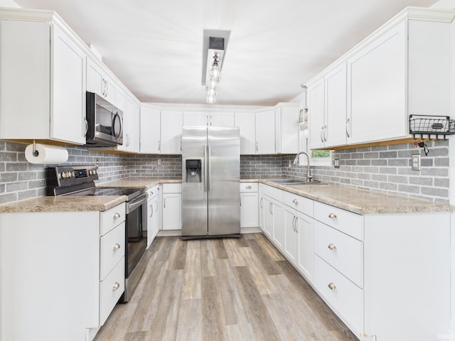 203 E Plum St, Frankton, IN 46044 - kitchen featuring appliances with stainless steel finishes, decorative backsplash, light wood-type flooring, and white cabinetry
