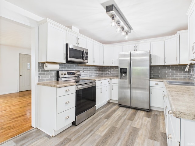 203 E Plum St, Frankton, IN 46044 - kitchen featuring appliances with stainless steel finishes, light wood-type flooring, light countertops, decorative backsplash, and white cabinetry