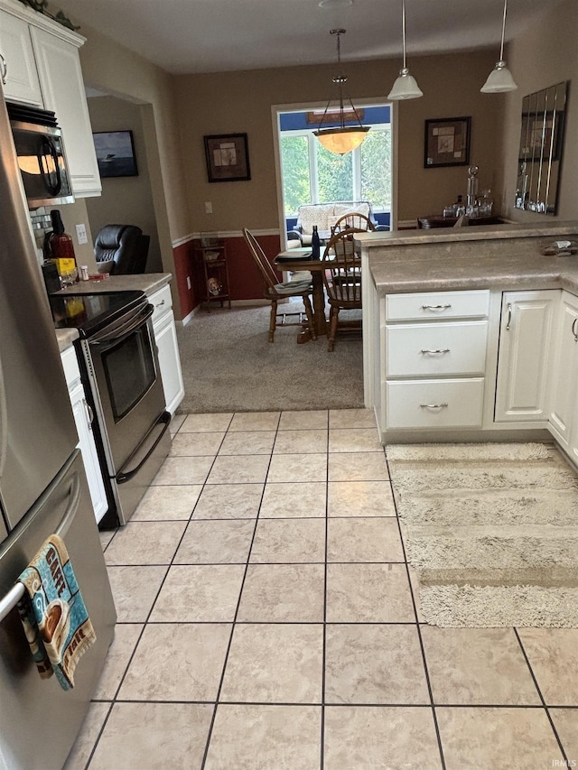6933 Cleopatra Xing, Fort Wayne, IN 46818 - kitchen with stainless steel appliances, white cabinetry, light tile patterned floors, pendant lighting, and wainscoting
