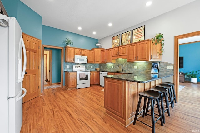 16619 Amethyst Pkwy, Fort Wayne, IN 46845 - kitchen with white appliances, a peninsula, tasteful backsplash, light wood-style flooring, and recessed lighting