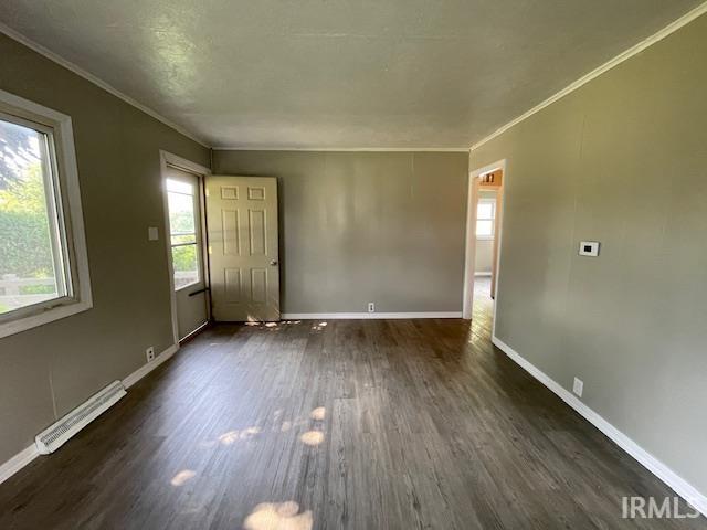 106 N Wellington St, South Bend, IN 46619 - unfurnished living room featuring crown molding, dark wood-style floors, and a baseboard heating unit