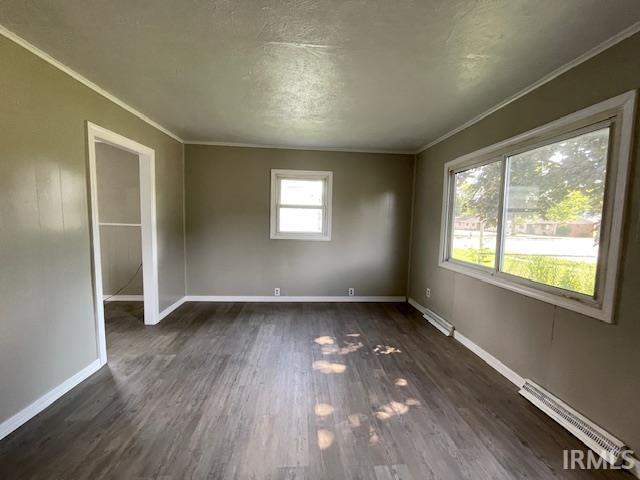 106 N Wellington St, South Bend, IN 46619 - spare room featuring dark wood-style floors, ornamental molding, and baseboard heating