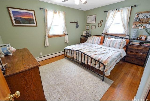 7132 W 350 N, West Lafayette, IN 47906 - bedroom with a baseboard heating unit, multiple windows, wood finished floors, and a ceiling fan